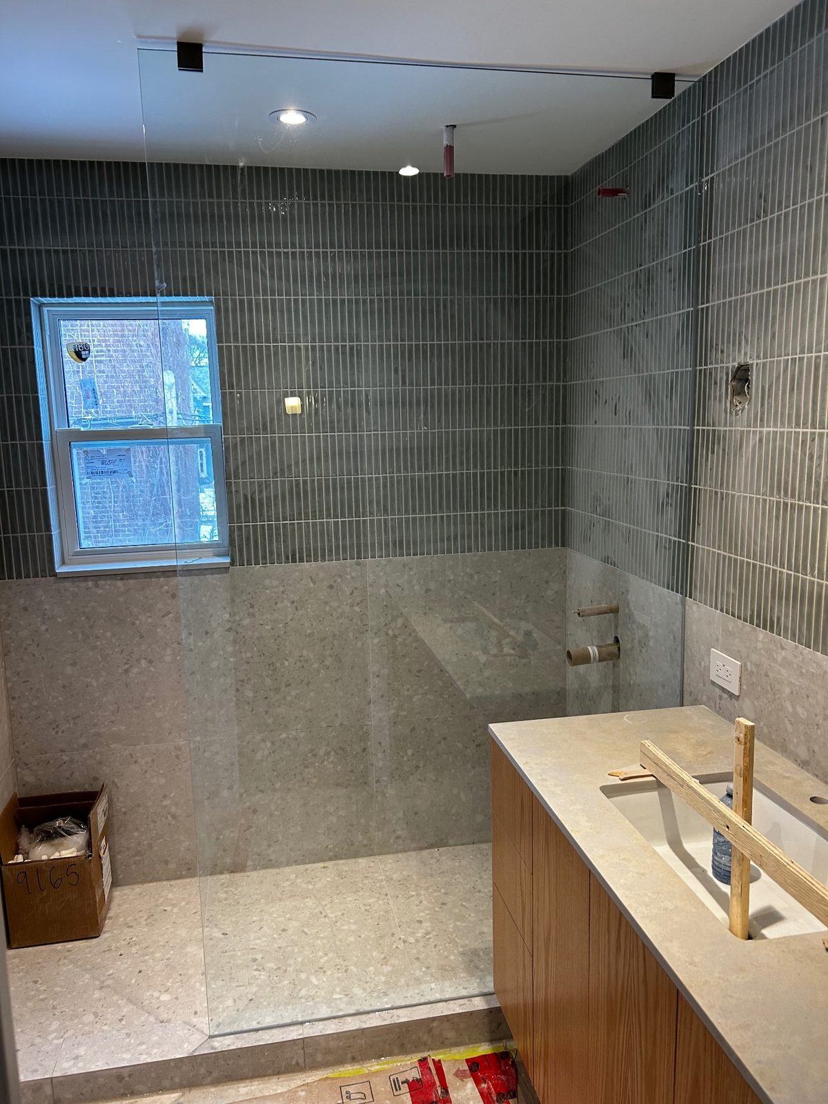 Walk-in shower with emerald kit-kat tile and terrazzo-look large-format tile