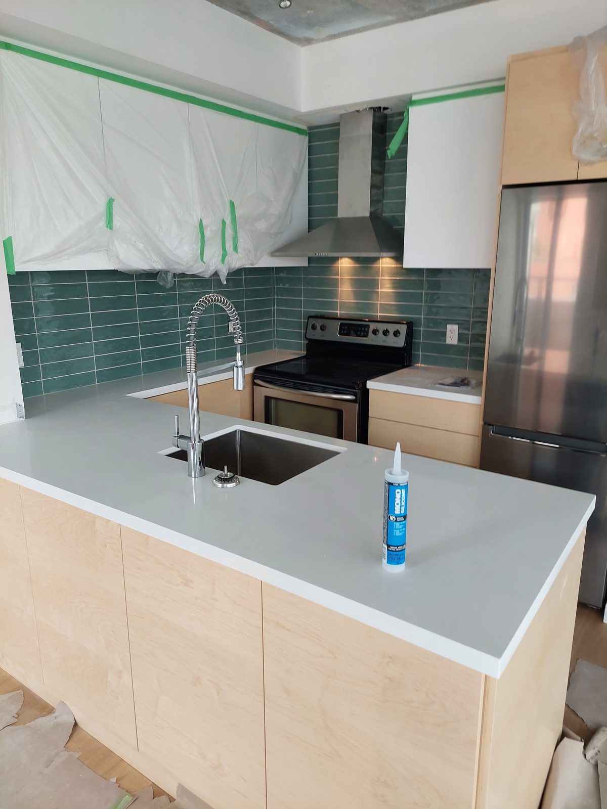 Kitchen with emerald subway tile backsplash and island sink